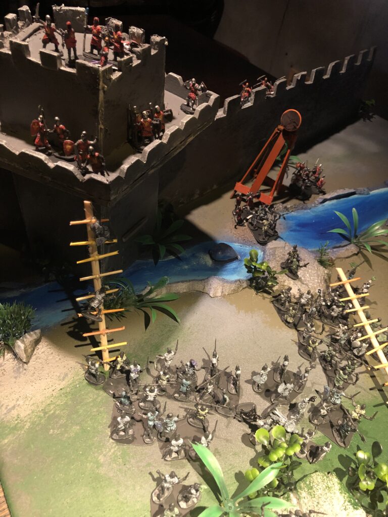Miniatures gaming soldiers scale miniature castle at Nevermore Game Club